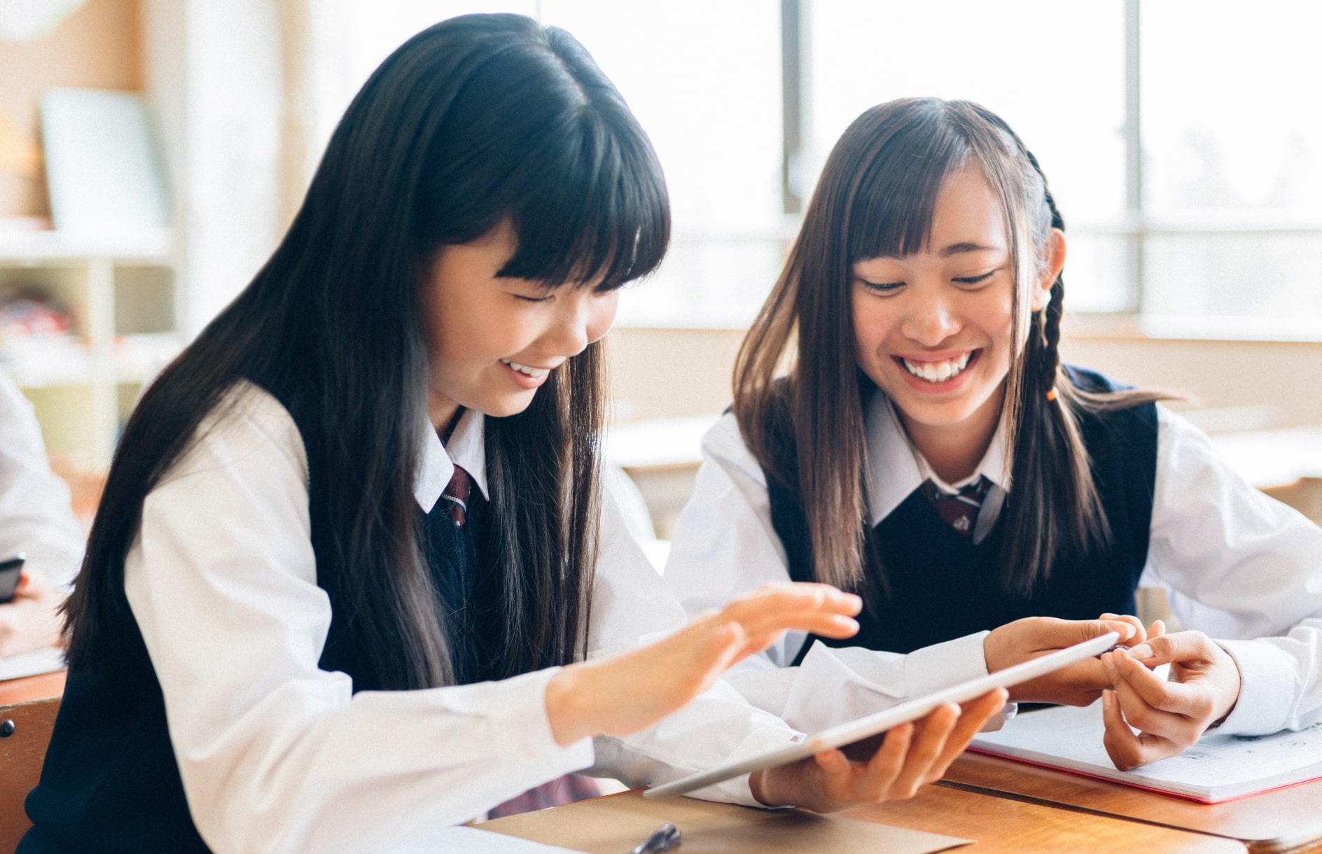 笑顔でタブレットを操作する2人の女子生徒の写真