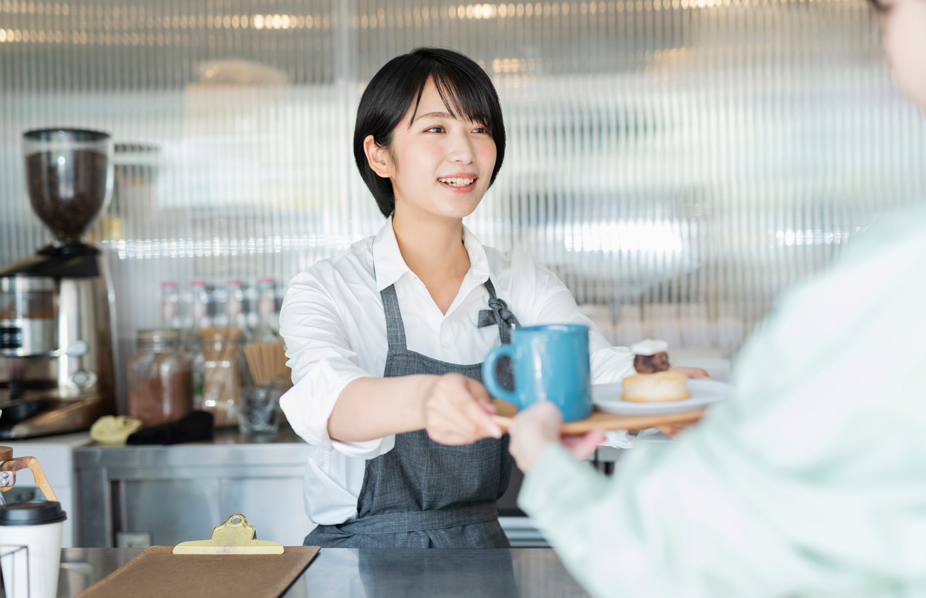 カフェで食事をお客様に手渡している女性の写真