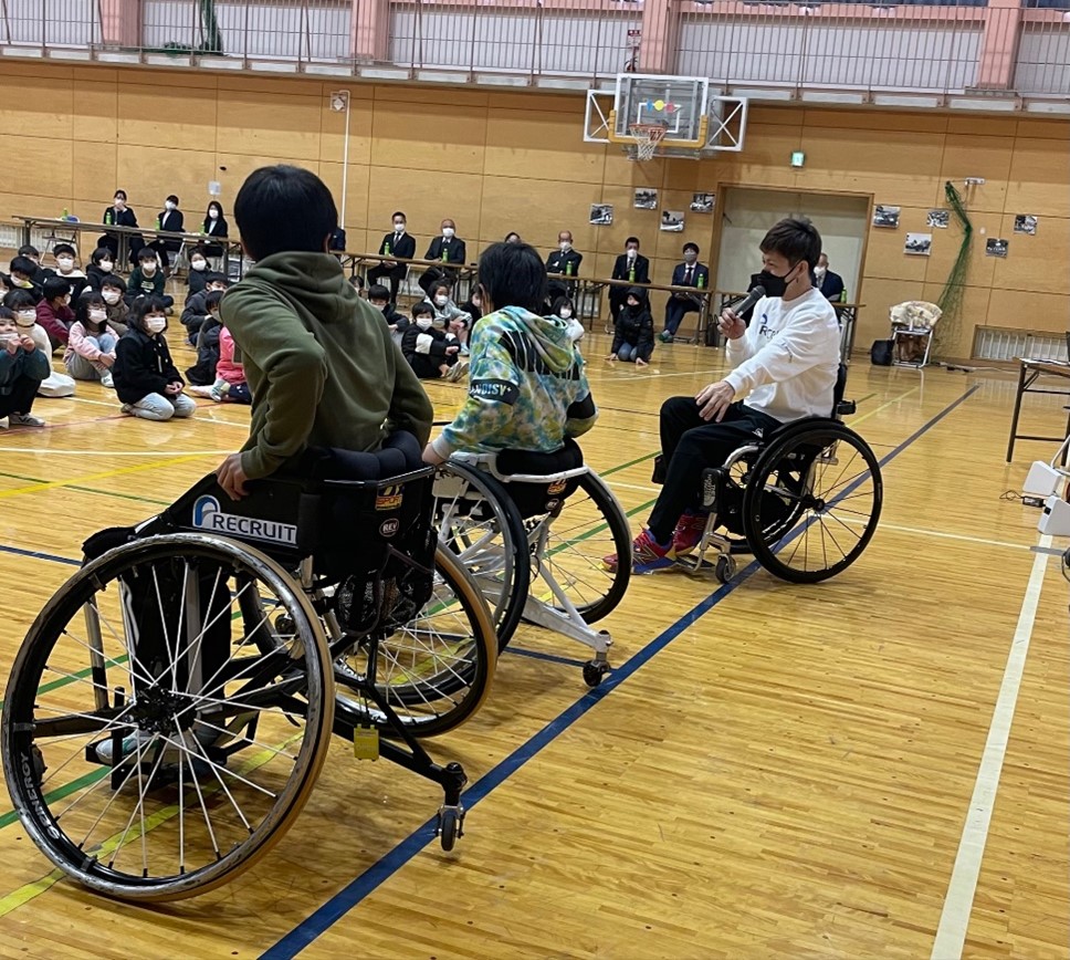競技用車いすテニス車に乗る6年生と、説明をする菅野 浩二選手